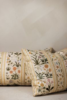 two pillows sitting on top of a bed next to each other in front of a white wall