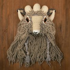 an animal made out of yarn on top of a wooden floor next to a wall