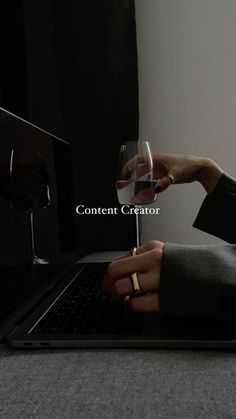 someone holding a wine glass in front of a laptop