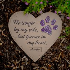 a heart shaped stone with a dog's paw painted on it and the words, no longer by my side, but forever in my heart