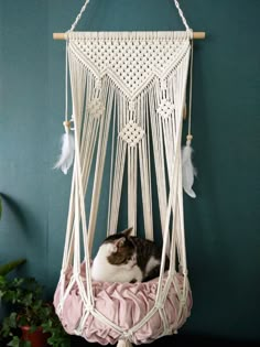 a cat laying in a hammock with feathers hanging from it's sides