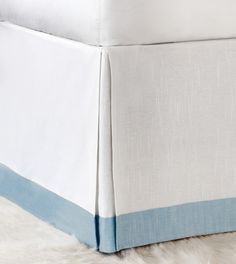 a bed with white sheets and blue trim on the bottom half is shown in this image