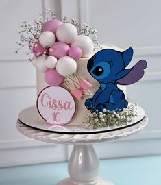 there is a cake decorated with balloons and an elephant on the top tier, as well as a name plate