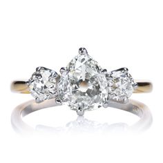 three stone engagement ring with an oval cut diamond in the center and two pear shaped diamonds on each side