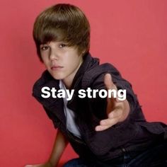 a young man sitting on the ground with his hand up and pointing at something in front of him that says stay strong