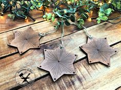 three metal star ornaments are hanging on a wooden table