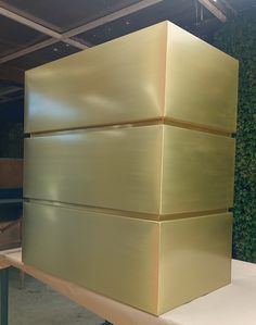 a large golden box sitting on top of a white table next to a green wall