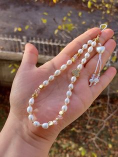 a hand holding a long white beaded necklace