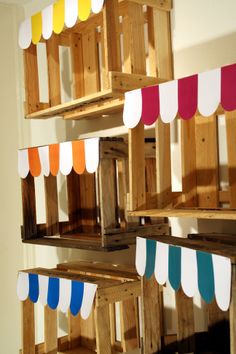 several wooden shelves with different colored paper hanging from the top, and below them is a white wall