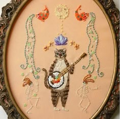 an embroidered artwork with a cat playing the guitar