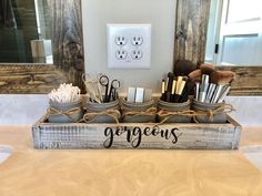 a wooden box filled with makeup brushes on top of a counter next to a light switch