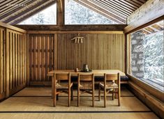 a wooden table and chairs in a room with wood paneling on the walls, along with large windows