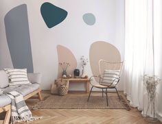 a living room with two chairs and a rug in front of the wall painted with abstract shapes