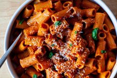 a white bowl filled with pasta covered in sauce and parmesan cheese