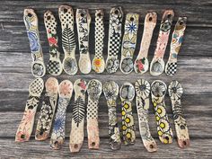 several spoons are lined up on a wooden table with designs painted on them and one is empty