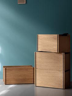 two wooden boxes sitting next to each other on the floor in front of a blue wall