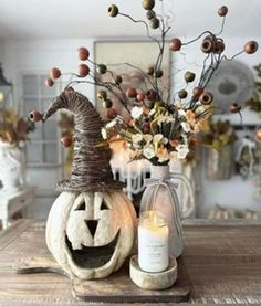 a table topped with a vase filled with flowers and pumpkins next to a candle