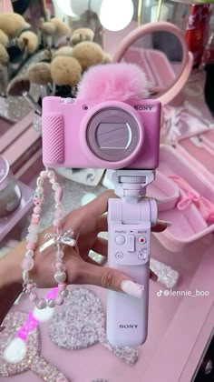 a pink camera is being held up in front of a mirror with other items on it