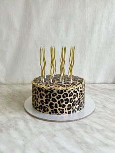 a leopard print cake with gold candles on top