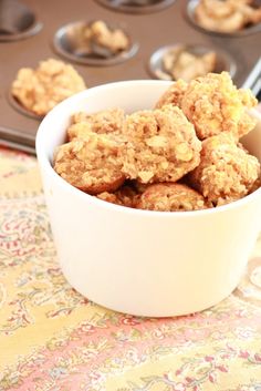 muffins in a white bowl on a table next to cupcake tins