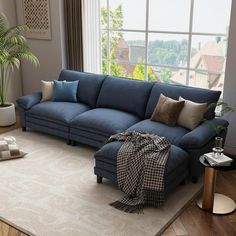 a living room with a large blue couch and pillows on the floor next to a window