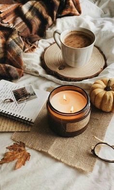 a cup of coffee sitting on top of a bed next to a book