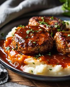 meatballs and mashed potatoes on a plate with gravy, garnished with parsley