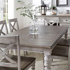 a dining room table with chairs and a vase filled with flowers