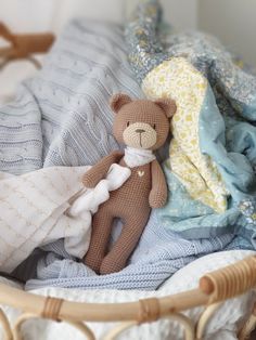 a brown teddy bear laying on top of a bed next to a pile of blankets