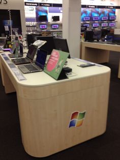 a laptop computer sitting on top of a wooden desk in a store next to other electronic devices