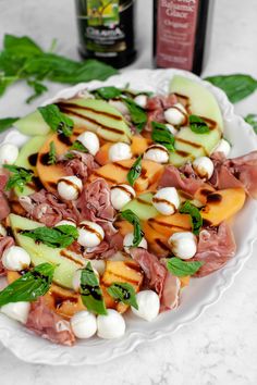 a white plate topped with meat and veggies next to a bottle of wine