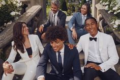 a group of men and women sitting on steps in front of white flowers with one man smiling at the camera