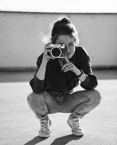 a woman kneeling down holding a camera up to her face