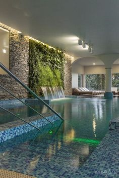 an indoor swimming pool with stairs leading up to it and a waterfall in the middle