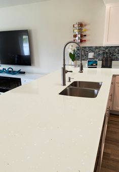 a kitchen with a white counter top next to a tv mounted on the wall above it