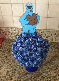 a cookie monster is sitting on top of a pile of chocolate candies in a blue cup