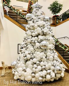 a christmas tree made out of balloons and silver balls in the middle of a lobby