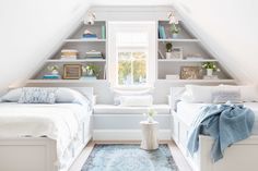 two beds in a room with white walls and carpeted flooring, built - in bookshelves