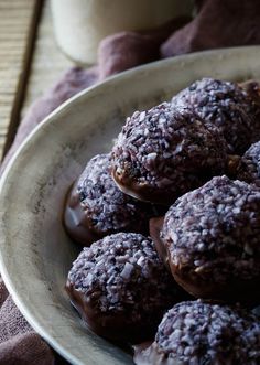 a bowl filled with chocolate covered donuts on top of a table