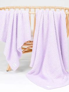 a baby crib with a purple blanket on top of it and a white background