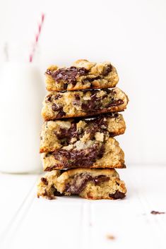 a stack of chocolate chip cookies next to a glass of milk