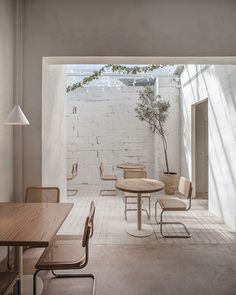 an indoor dining area with white brick walls and wooden tables, chairs, and potted plant