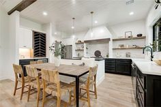 a dining room table and chairs in front of an open kitchen area with white walls