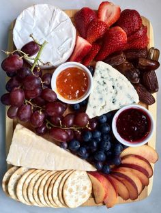 a cheese board with grapes, strawberries and crackers