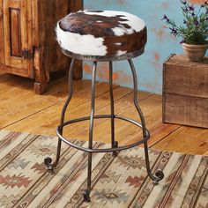 a stool with a cowhide seat on top of it next to a potted plant