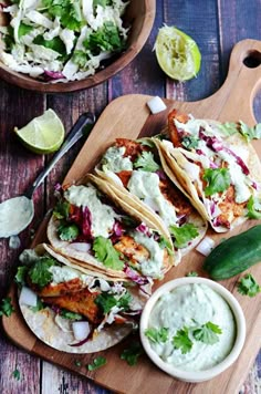 chicken tacos with guacamole and salsa on a cutting board next to lime wedges