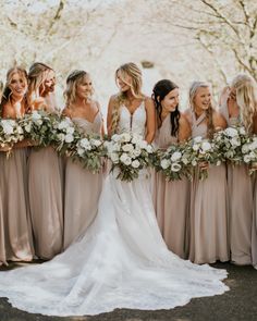 a group of women standing next to each other wearing dresses and holding bouquets in their hands