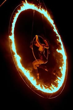 a man is doing tricks on fire with a hula hoop in front of him