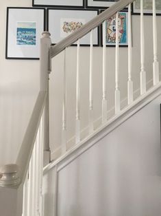 a white staircase with pictures on the wall