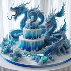 a three tiered cake decorated with blue frosting and two dragon figurines